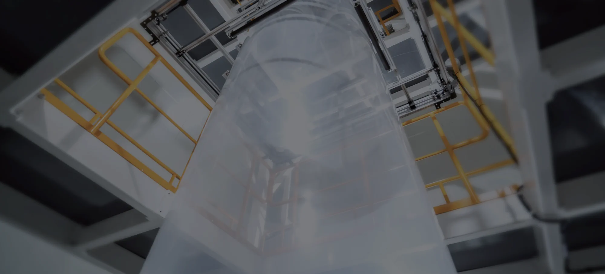 Film bubble rising between the platform rails of a blown film line, seen from below