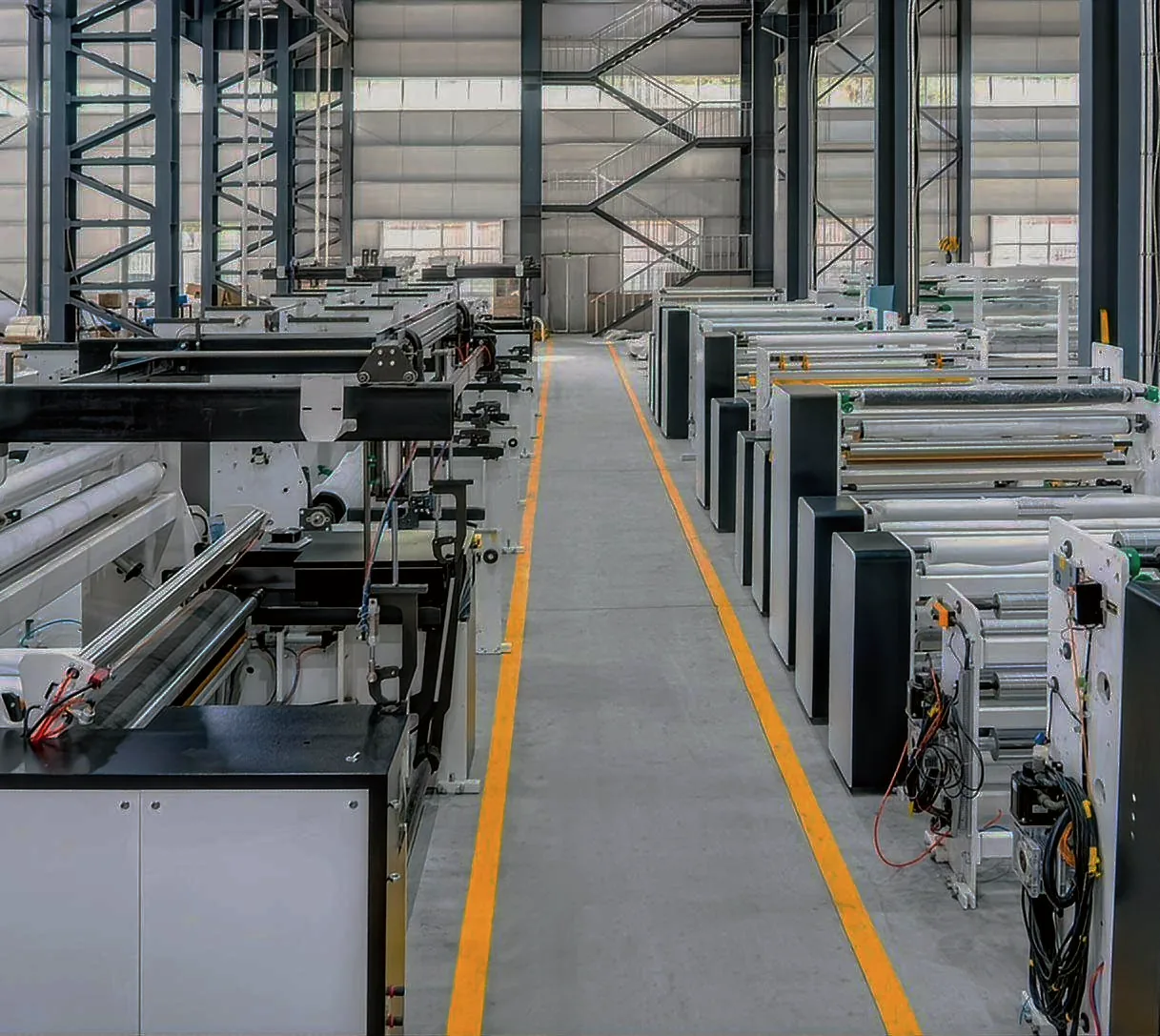 Bag making machines lined up along both sides of the workshop aisle