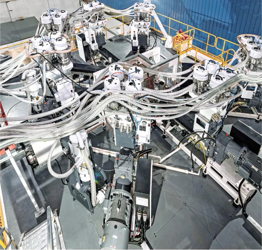 Looking down on the stack die from the platform: dosing units and feed lines around it, extruders and drives below